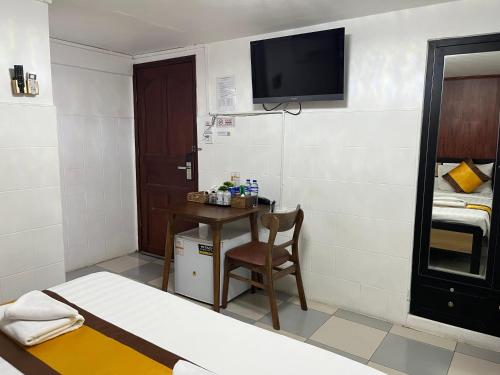 a room with a bed and a desk and a tv at Sun Chakra Boutique Hotel - 50m to Museum & Royal Palace & Walking street in Phnom Penh