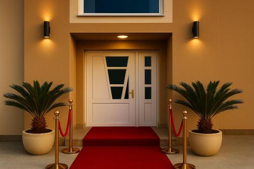 a red carpet leading to a door with two plants at Apartmani Enydoo in Ulcinj