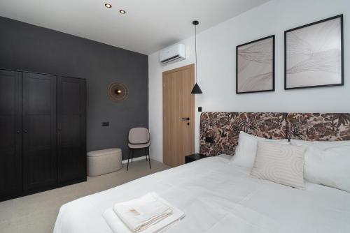 a bedroom with a white bed and a chair at Villa Lapidea in Vodice