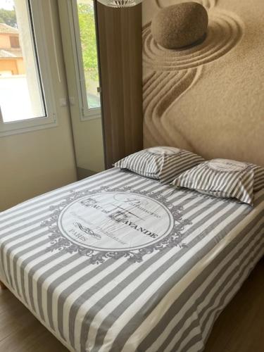 - un lit avec une couette blanche et noire et une fenêtre dans l'établissement L'Ostal de Jacou, à Jacou