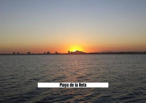 a sunset over the water with a sign that says play me lie me hug at Apartalux San Pedro Mar in San Pedro del Pinatar