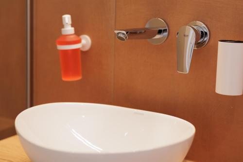 a white sink in a bathroom with a red bottle at Dominoes Corfu in Ýpsos