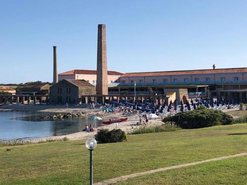 a group of people sitting on the beach in front of a factory at Villetta sul Mare in Stintino