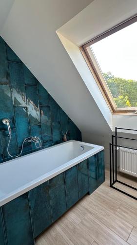 a bathroom with a bath tub with a large window at Dom wakacyjny z basenem i sauną GWIZD Ustronie Morskie in Grąbnica