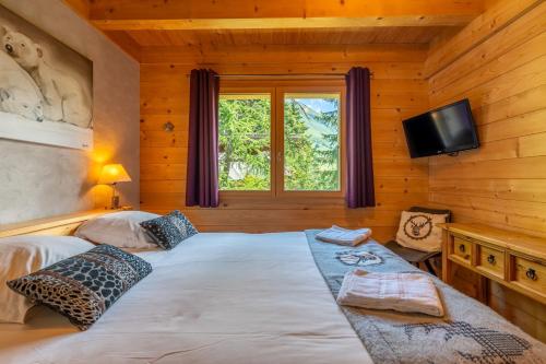- une chambre avec un grand lit dans une cabane en bois dans l'établissement Coeur de Samance, au Grand-Bornand