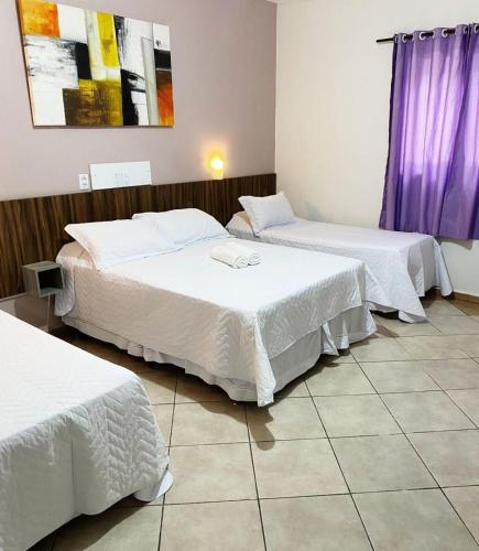 two beds in a hotel room with white sheets at Itaipu Hotel in Foz do Iguaçu