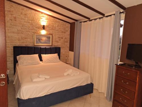Un dormitorio con una cama con sábanas blancas y un televisor. en Posidi pool apartment, en Possidi