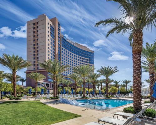 a resort pool with palm trees and a tall building at Wyndham Desert Blue 2BR Villa with Resort Access in Las Vegas