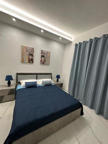 a bedroom with a large bed with blue sheets at Vitale House in Borgetto