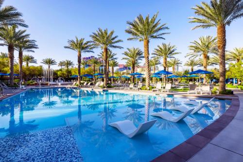 a swimming pool with palm trees and blue umbrellas at Wyndham Desert Blue 3BR Villa with Resort Access in Las Vegas