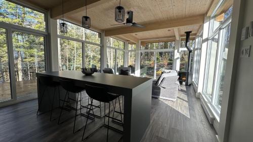 a kitchen with a island in a room with windows at Scenic Bright - Sauna - Fire - 20 min Tremblant in La Conception