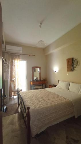 a bedroom with a large bed and a living room at Ενοικιαζόμενα δωμάτια "ΟΛΓΑ" in Loutra Ipatis