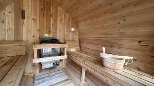 a wooden interior of a sauna with a bucket at Scenic Bright - Sauna - Fire - 20 min Tremblant in La Conception