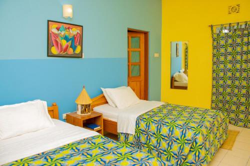 Usa RiverにあるKilimanjaro Eco Lodgeの黄色と青の部屋にベッドが2つ