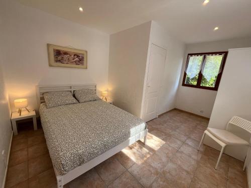 una camera da letto con un letto, una sedia e una finestra di La Cigalière - Appartement Rez-de-Jardin a Vallauris