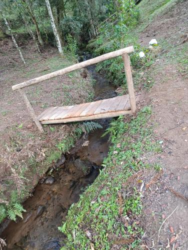 a wooden bench sitting on top of a creek at Casa Cipreste no Refúgio Pinheiro Beira Rio in Sapucaí-Mirim