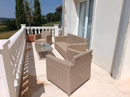 two wicker chairs and a table on a balcony at Le Charme des Bastides in Castelnau-de-Montmiral