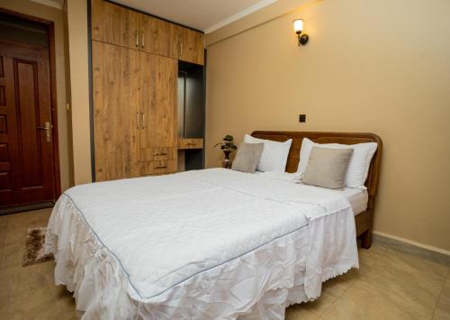 a bedroom with a large bed with white sheets at Edrin Apartments in Kampala