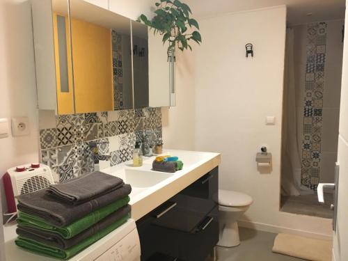 La salle de bains est pourvue d'un lavabo et de toilettes avec des serviettes. dans l'établissement Appartement Yucca entre Mer Montagne, à Pérols