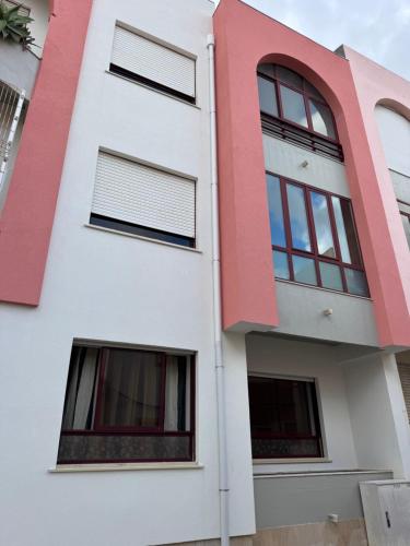 a white and red building with windows at Cozy Abadias Apartment in Figueira da Foz