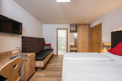 a hotel room with a bed and a couch at Hotel Anewandter in Brunico