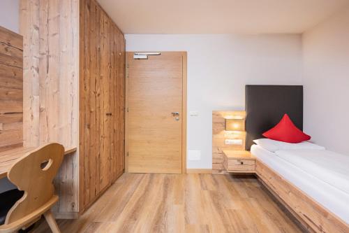 a bedroom with a bed with a red pillow on it at Hotel Anewandter in Brunico