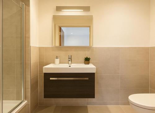 a bathroom with a sink and a mirror at Bright Studio Flat - Walk to River Thames & Kingston Town in Surbiton