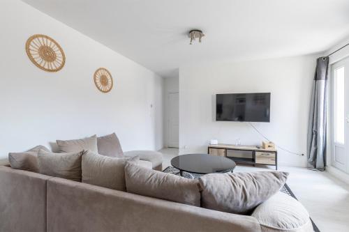 a white living room with a couch and a tv at Maisonnette 2 Un Séjour à Part in Longeville-lès-Metz