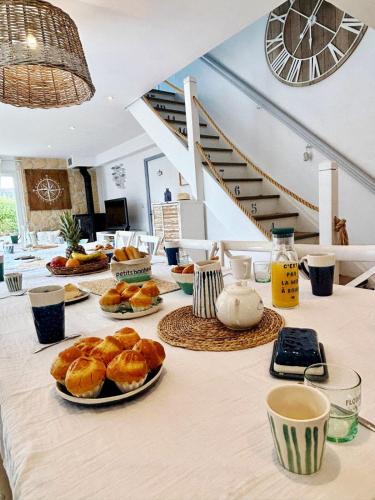 a table with plates of pastries and coffee and stairs at La villa Ty Mor Braz in Plouarzel