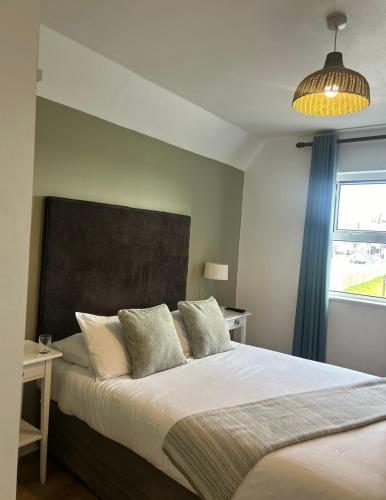 a bedroom with a large bed and a window at Maddens Bridge Bar & Guesthouse in Bundoran