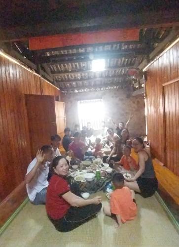 a group of people sitting around a table in a room at Triệu hoan homestay nhà sàn cổ tại làng đá cổ Khuổi ky in Dam Thuy