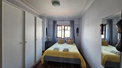 a room with a bed with yellow sheets and a mirror at Historic center apartment Cascais in Cascais
