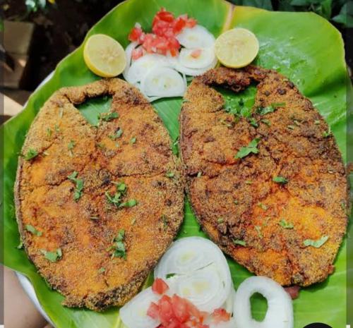 a green plate with two pieces of meat and onions at Sai Ganesh Cotteg in Alibag