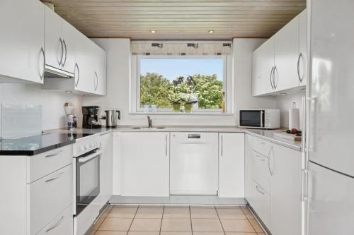 a kitchen with white cabinets and a window at Energy-Efficient Pool House Located Between The Sea And The Fjord in Ringkøbing