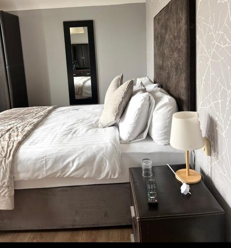 a bedroom with a bed with white sheets and a mirror at Maddens Bridge Bar & Guesthouse in Bundoran