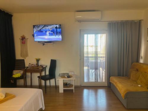 a living room with a couch and a tv on the wall at Studio apartman Mirjam in Jadranovo