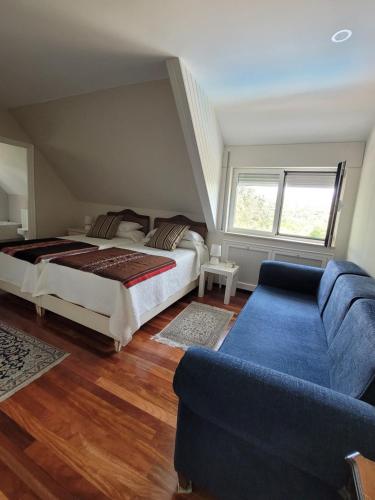 a bedroom with a bed and a blue couch at Casa ESPLIEGO in Torrelodones