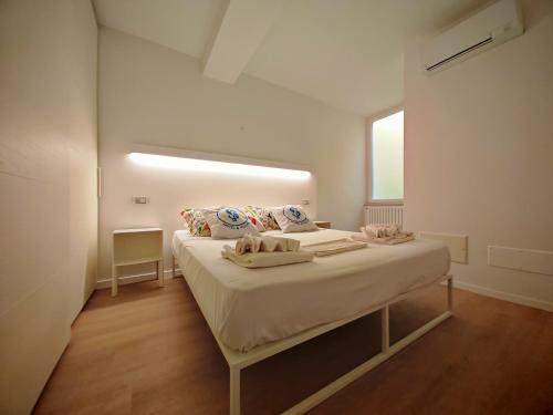 a white bedroom with a bed with a window at SG Luxury - Pieds dans l eau Torri in Torri del Benaco