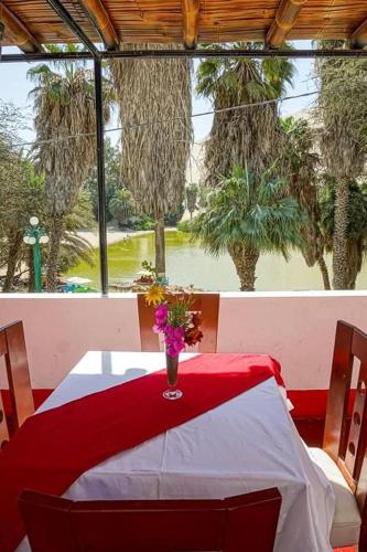 a red and white table with a vase of flowers on it at Hospedaje con vista ala laguna de huacachina refugio en el oasis in Ica