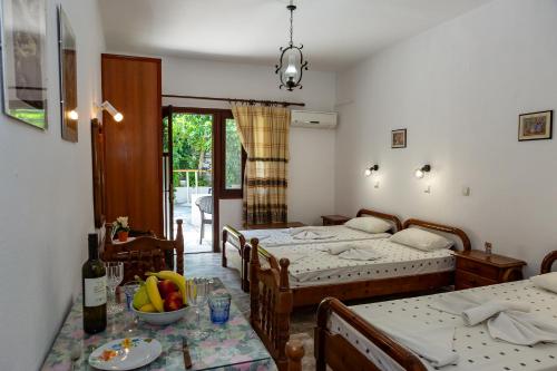 a bedroom with two beds and a table with a bowl of fruit at FRINI APPARTMENTS in Kokkari