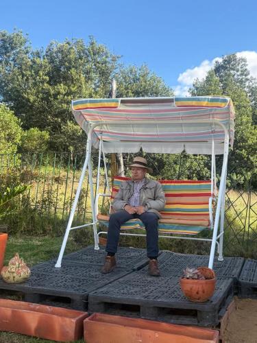 a man sitting on a bench under a gazebo at Altos del paraíso in Fúquene