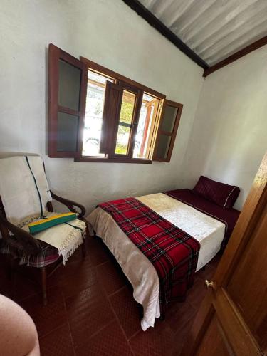 a bedroom with a bed and a chair and windows at Altos del paraíso in Fúquene