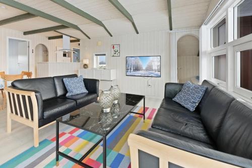 a living room with a black leather couch and a glass table at Lovely cottage on Rømø in Rømø