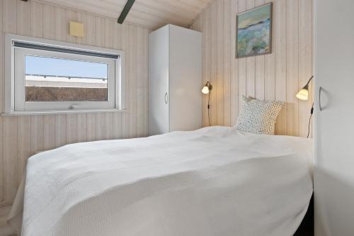 una camera da letto con un letto bianco e una finestra di Lovely cottage on Rømø a Rømø