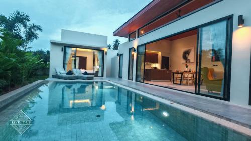 a villa with a swimming pool in front of a house at Santi Tara Villas in Amphoe Koh Samui