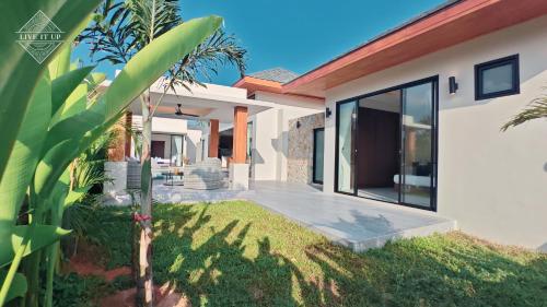 a white house with a porch and a patio at Santi Tara Villas in Amphoe Koh Samui