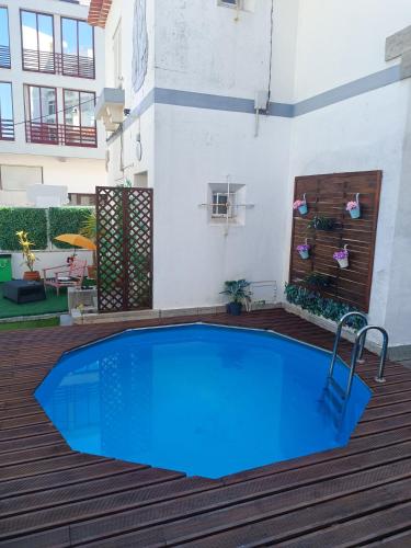 a large blue swimming pool on a wooden deck at Happy Day Beach House in Costa da Caparica