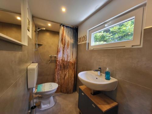 a bathroom with a sink and a toilet and a window at Bungalow Maya in Lauchhammer