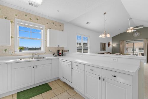 a large kitchen with white cabinets and a window at Stylish Barefoot Golf Condo with Pool Access in North Myrtle Beach