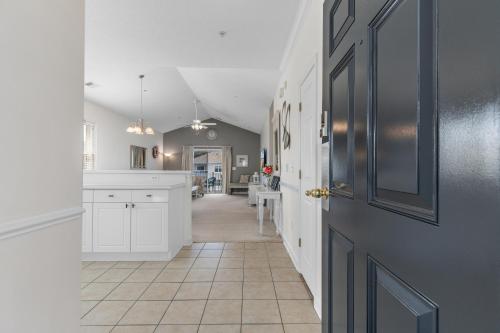 a kitchen with white cabinets and a door at Stylish Barefoot Golf Condo with Pool Access in North Myrtle Beach